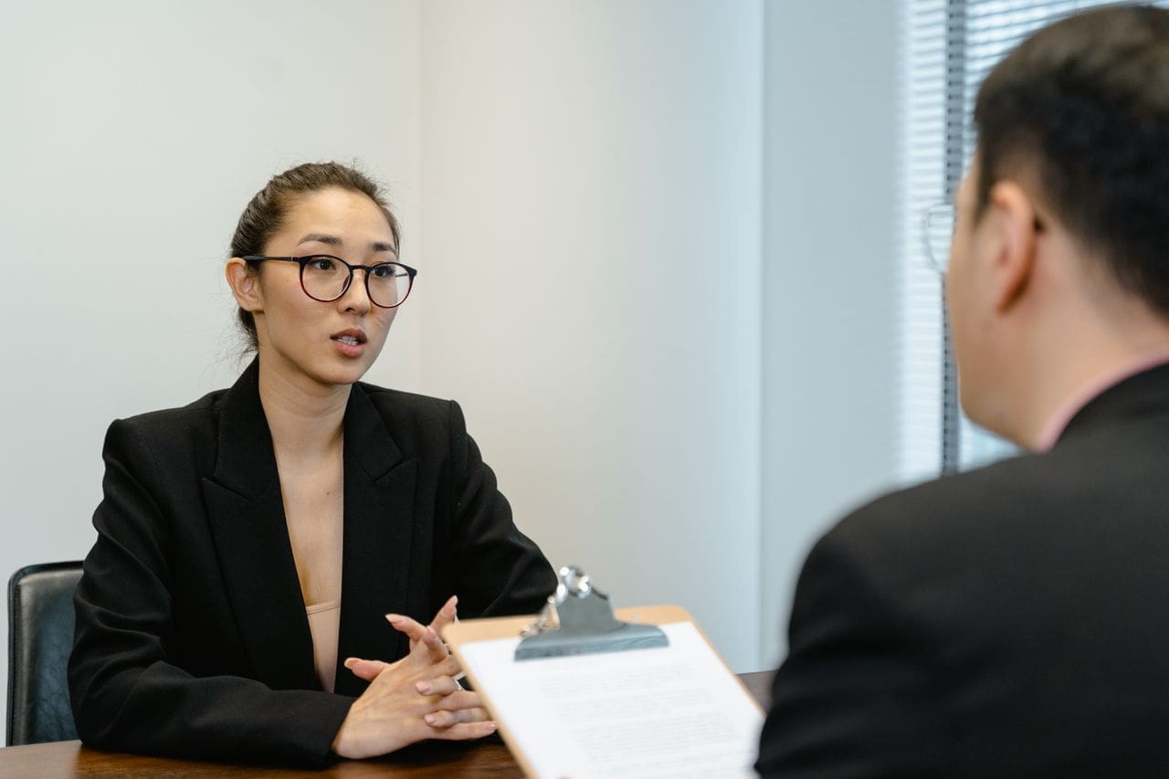 services-04 A focused interview scene in an office environment with business attire and a clipboard.